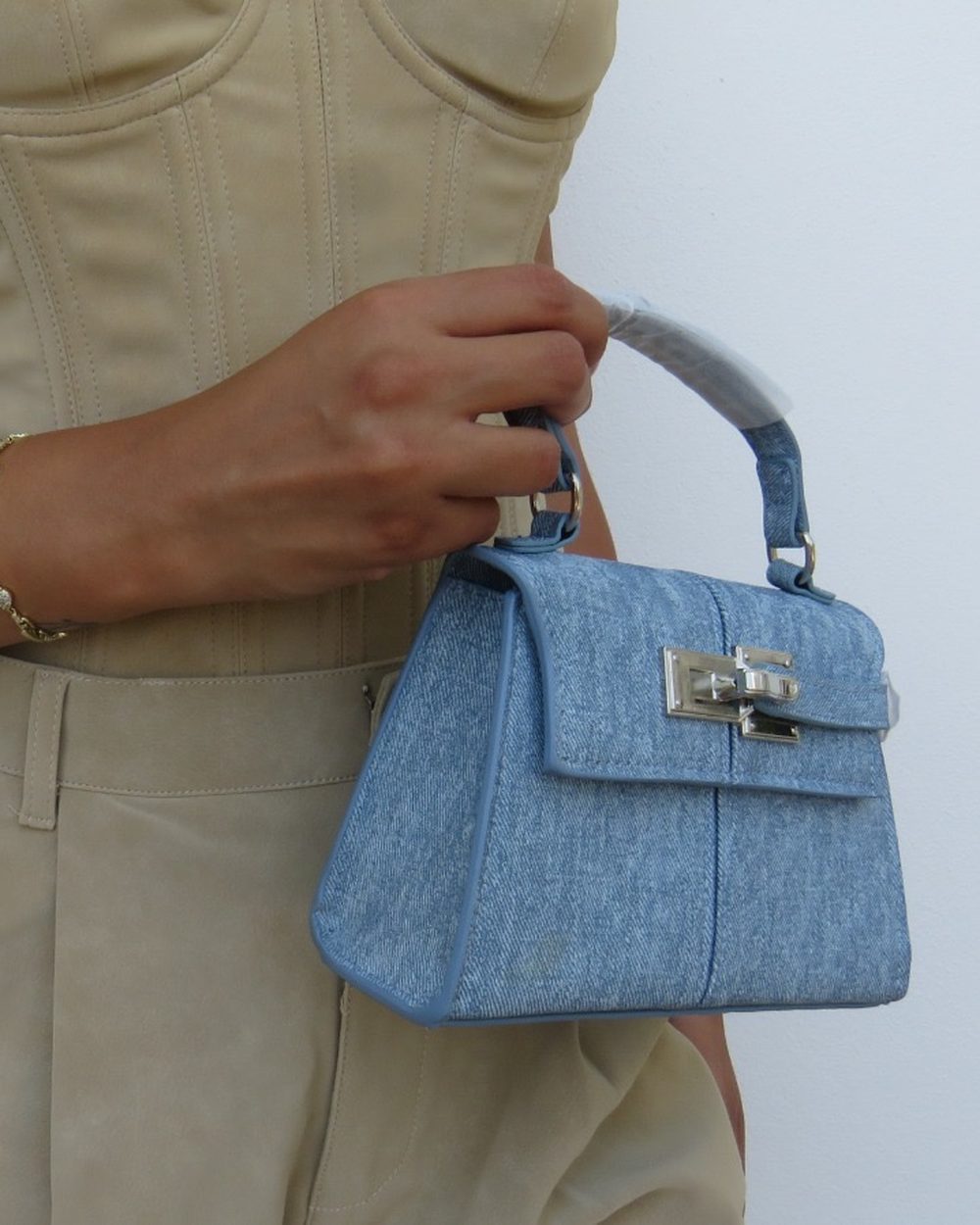 Mavi denim mini çanta, bej takım giyen bir modelin elinde